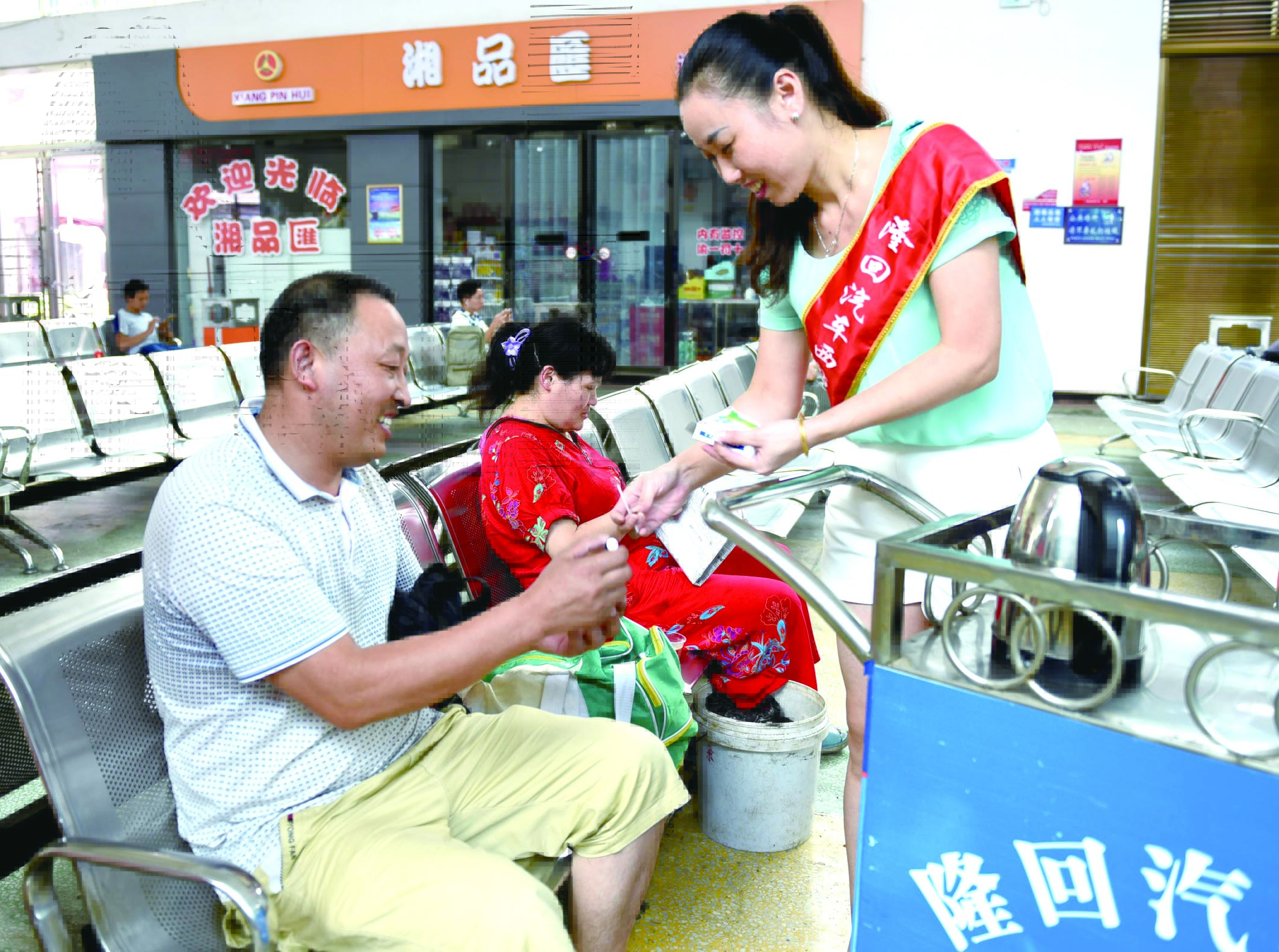 隆回分公司汽車西站工作人員正在為旅客免費(fèi)贈(zèng)送藿香正氣水。